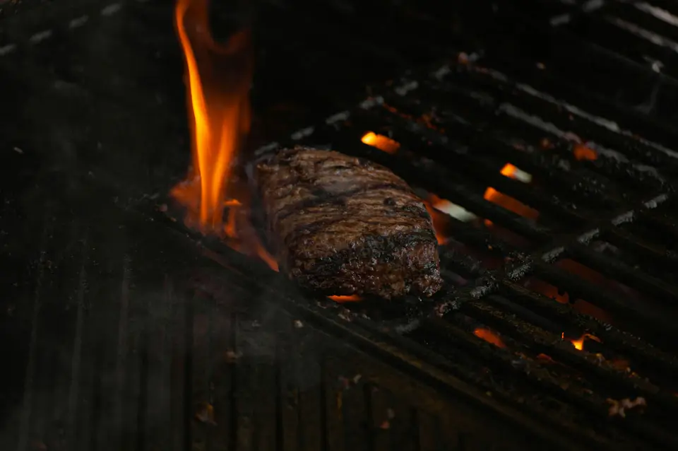 Een steak op de grill boven laaiende vlammen
